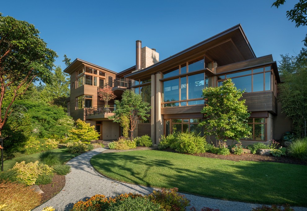 Photo of an expansive contemporary house exterior in Seattle with three floors, wood cladding and a lean-to roof.
