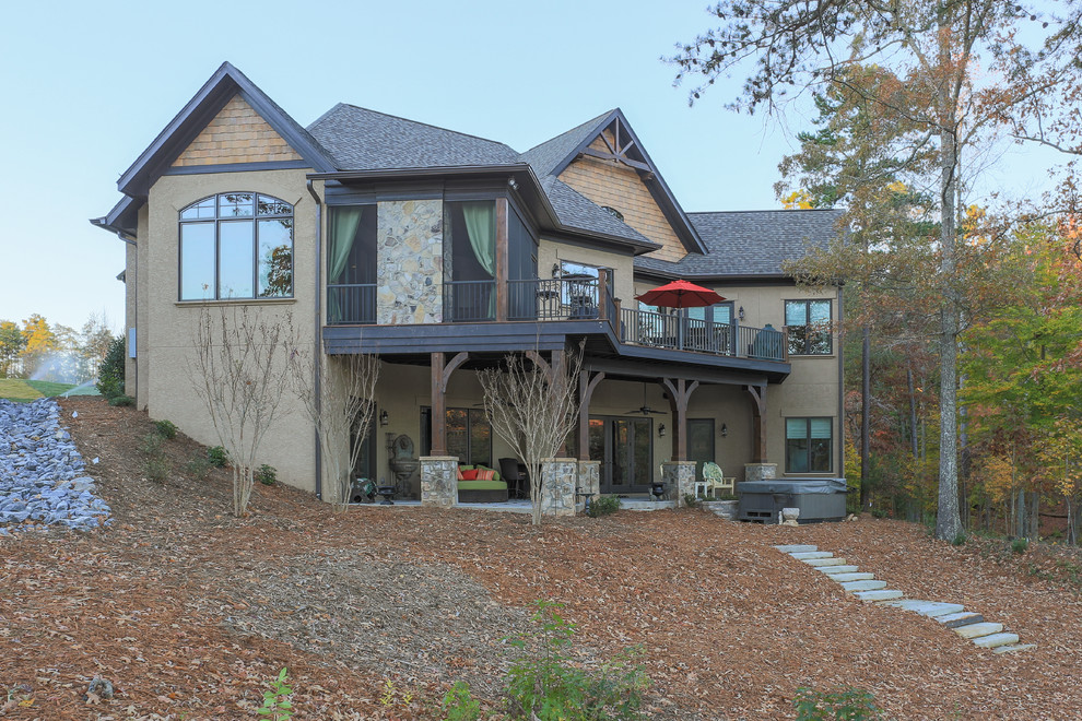 Cette photo montre une grande façade de maison beige montagne en stuc à un étage avec un toit à deux pans.