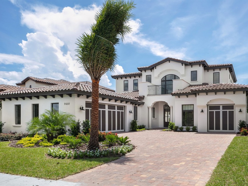 Example of a large transitional white two-story stucco house exterior design in Orlando with a tile roof and a hip roof