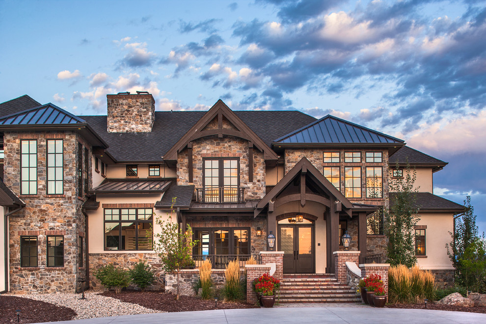 Стильный дизайн: большой, двухэтажный, бежевый дом в классическом стиле с облицовкой из камня и вальмовой крышей - последний тренд