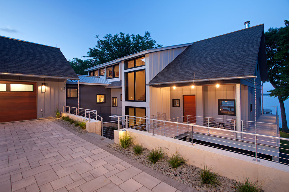 Cette image montre une façade de maison grise design en bois à un étage avec un toit en appentis.