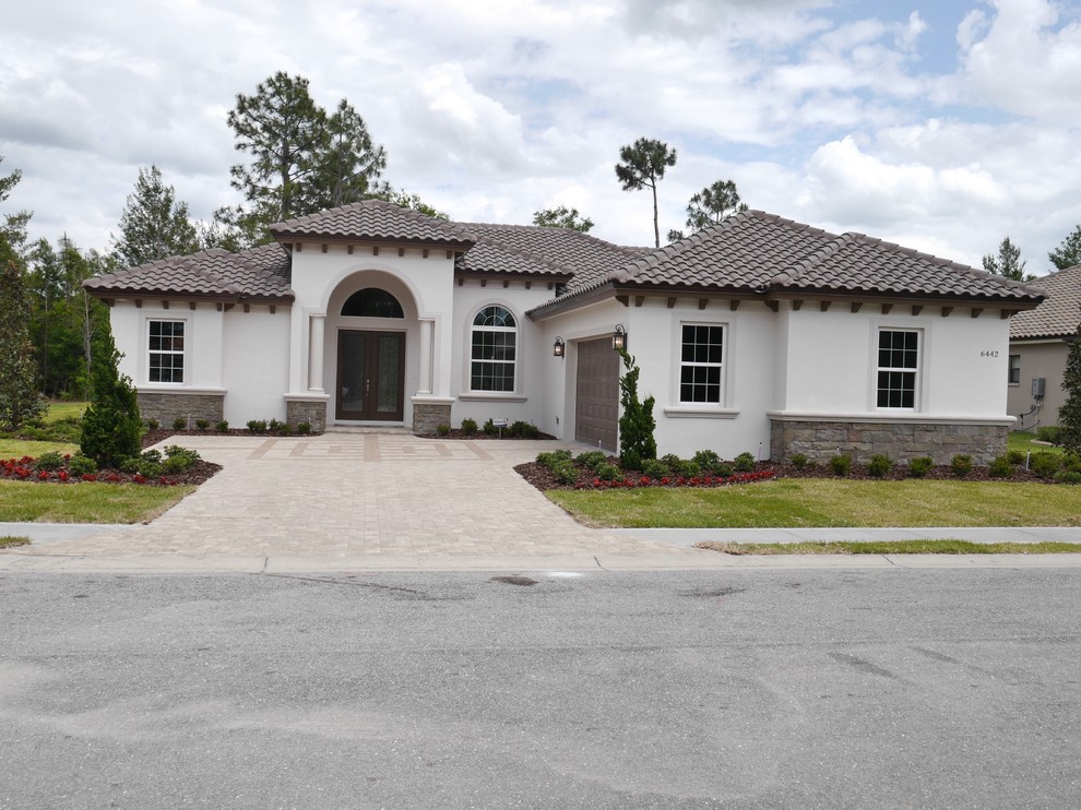 This is an example of a medium sized and beige traditional bungalow render detached house in Tampa with a hip roof and a tiled roof.