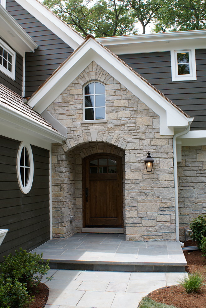 На фото: двухэтажный, серый дом в классическом стиле с облицовкой из камня и двускатной крышей с