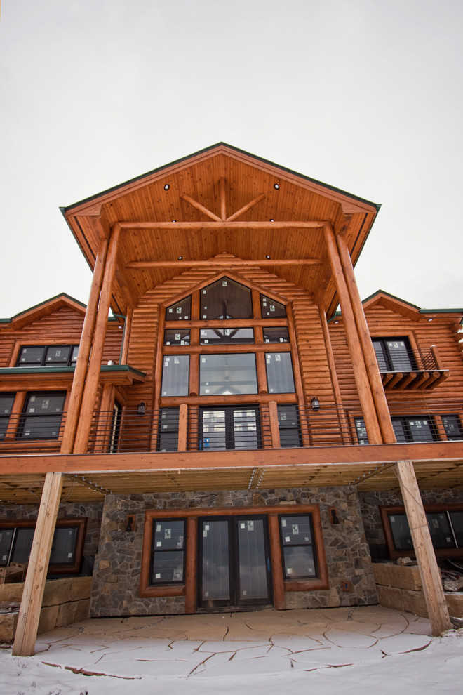 Cette image montre une très grande façade de maison marron chalet en bois à un étage avec un toit à deux pans et un toit en shingle.