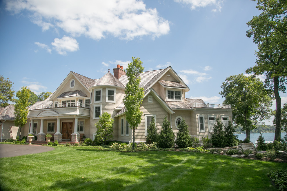 Large elegant beige two-story exterior home photo in Milwaukee with a shingle roof