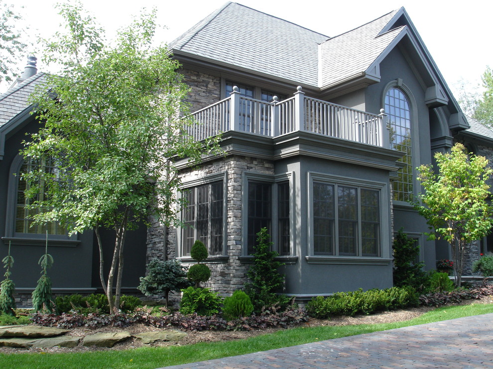 Huge traditional gray three-story stucco exterior home idea in Grand Rapids with a hip roof