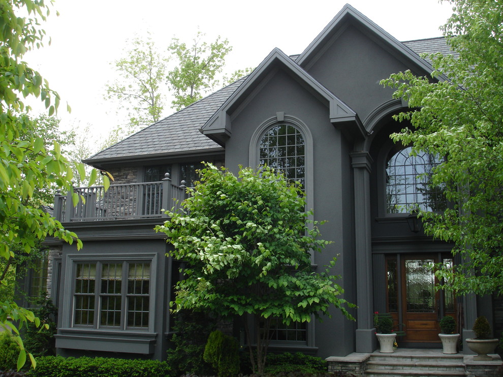 Diseño de fachada gris clásica extra grande de tres plantas con revestimiento de estuco y tejado a cuatro aguas