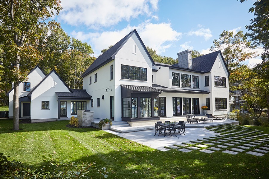 Réalisation d'une grande façade de maison blanche minimaliste en stuc à un étage avec un toit à deux pans, un toit en shingle et un toit noir.