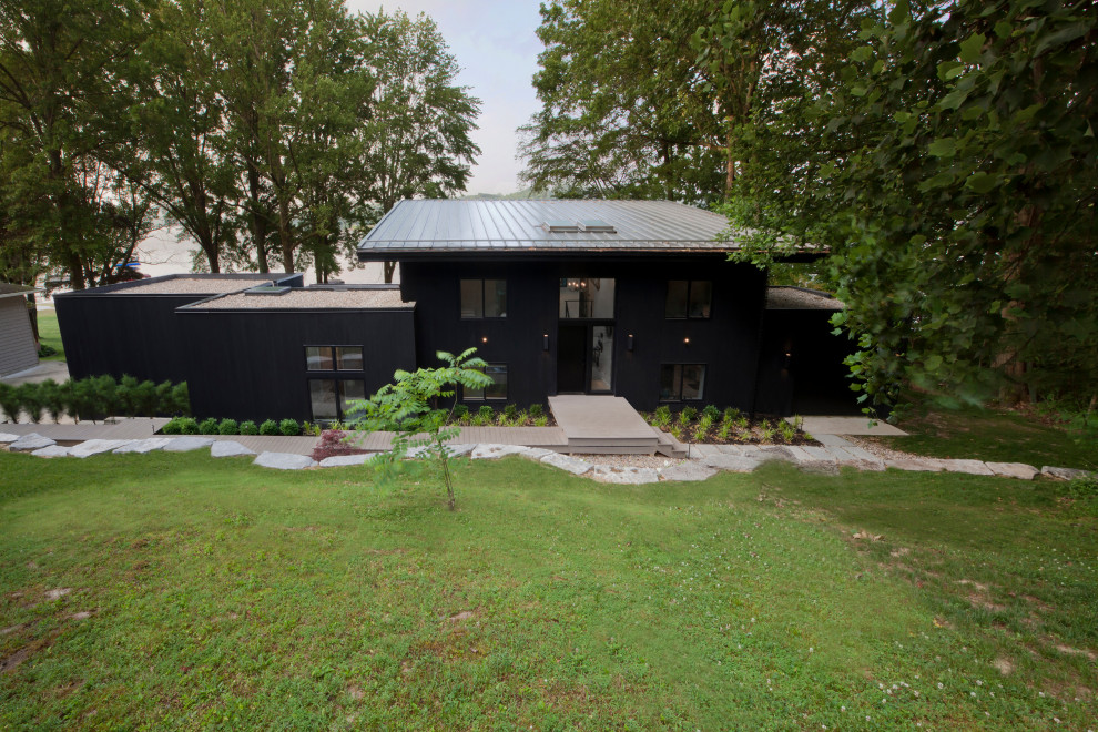 Idéer för ett mellanstort modernt svart hus, med två våningar, pulpettak och tak i metall