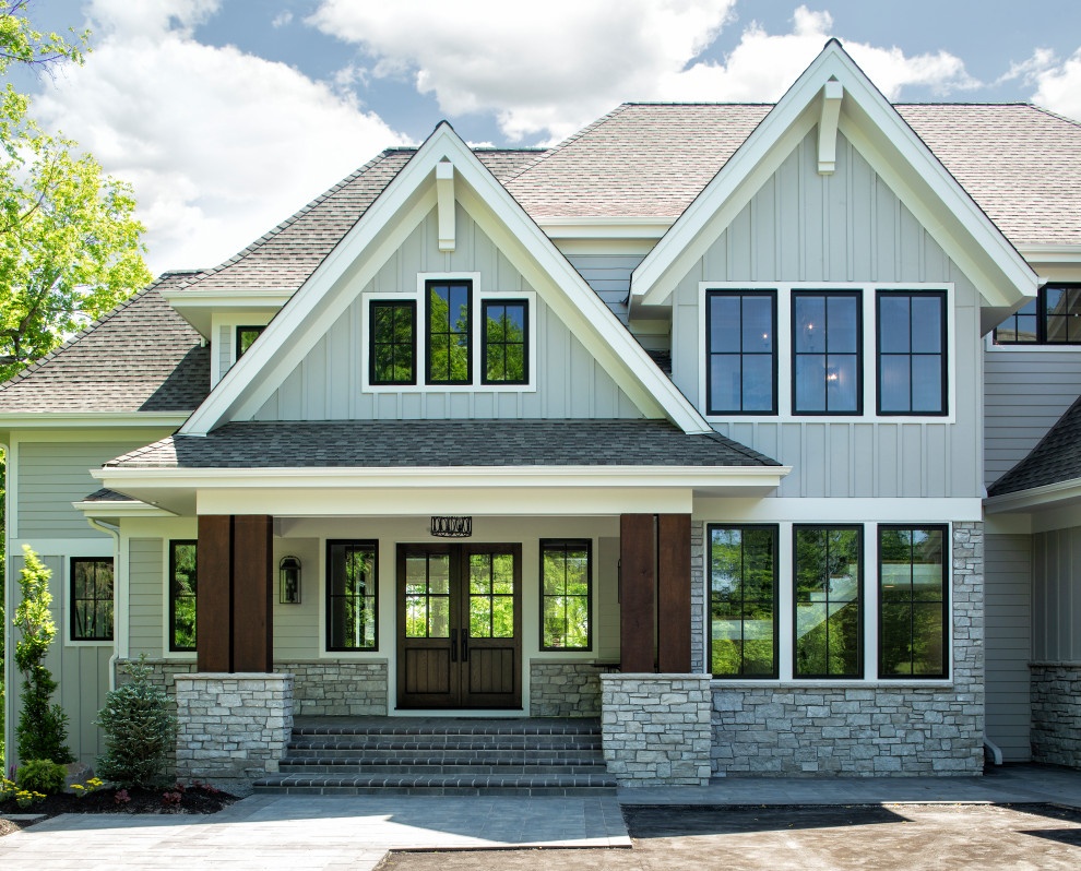 Ejemplo de fachada de casa gris clásica renovada grande de dos plantas con revestimientos combinados, tejado a dos aguas y tejado de teja de madera