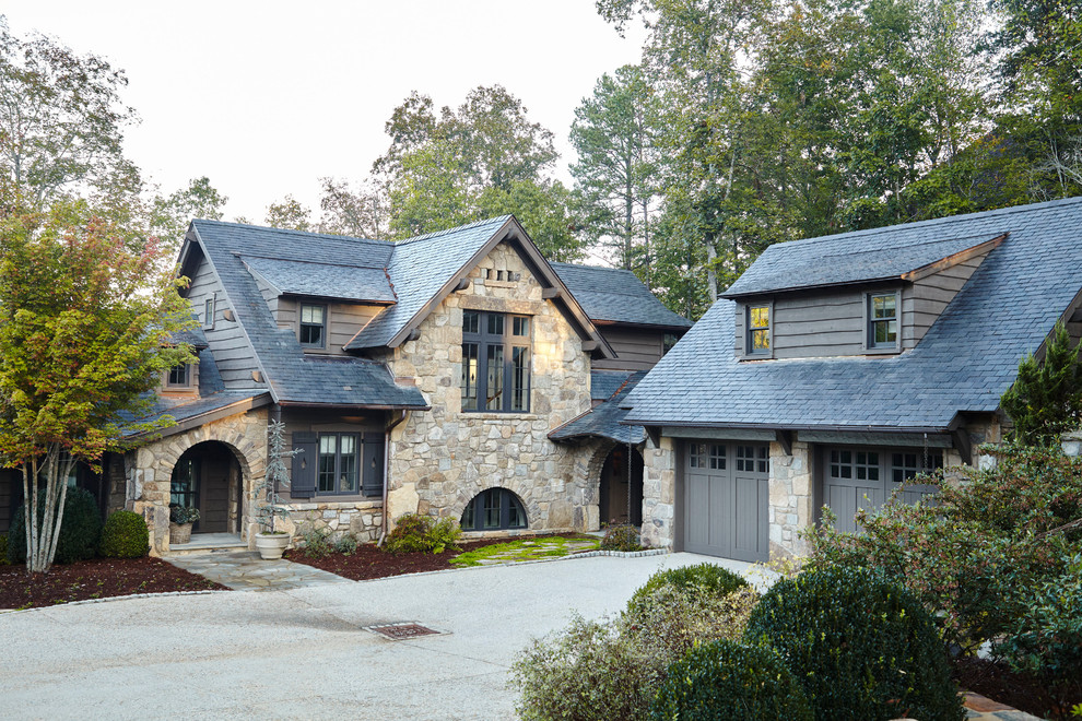 Réalisation d'une façade de maison beige chalet en pierre à un étage avec un toit à deux pans et un toit en shingle.