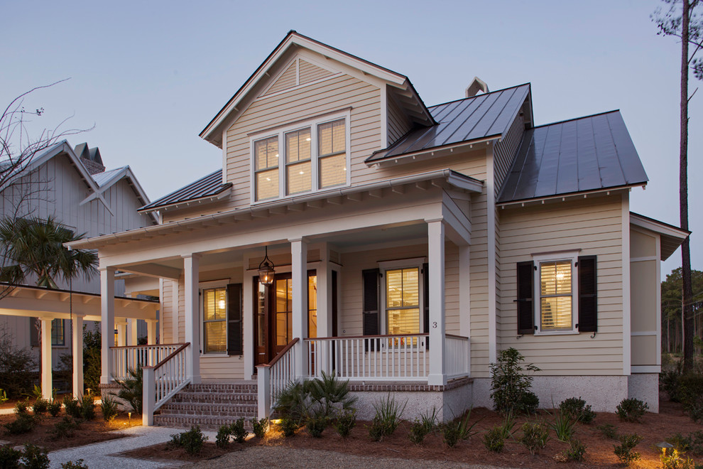 Imagen de fachada de casa beige marinera de dos plantas con tejado a dos aguas y tejado de metal