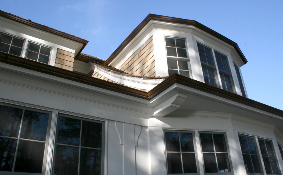 Exemple d'une grande façade de maison beige chic en bois à un étage avec un toit à quatre pans.