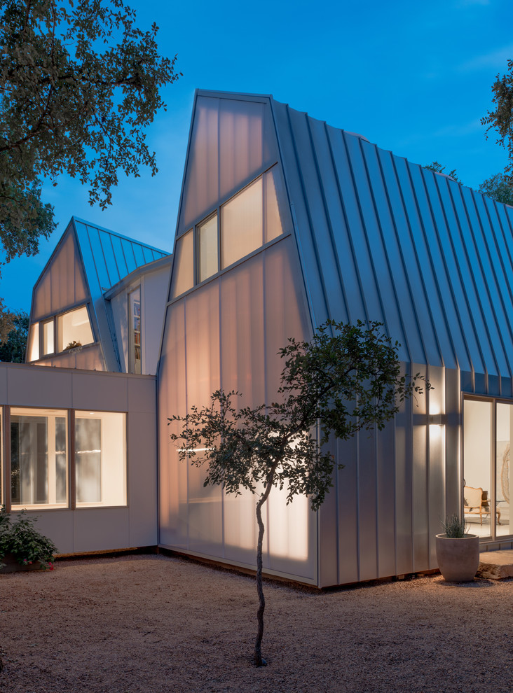 Zweistöckiges Modernes Haus mit Metallfassade, weißer Fassadenfarbe und Mansardendach in Austin