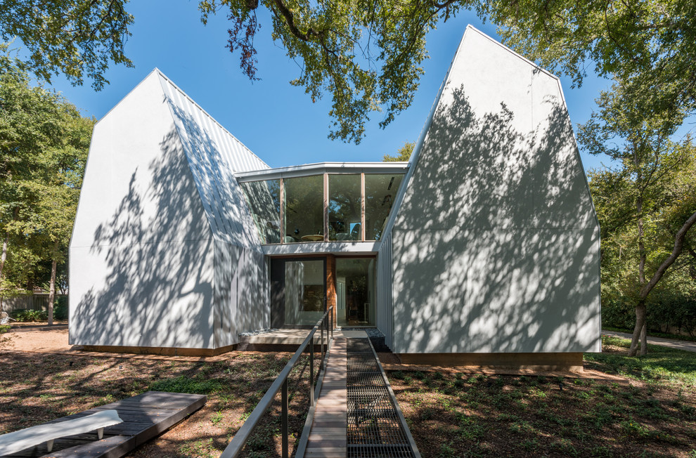 Cette image montre une façade de maison métallique et blanche minimaliste à un étage avec un toit de Gambrel.