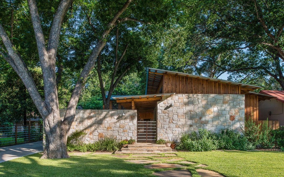 Small trendy one-story stone exterior home photo in Austin with a shed roof