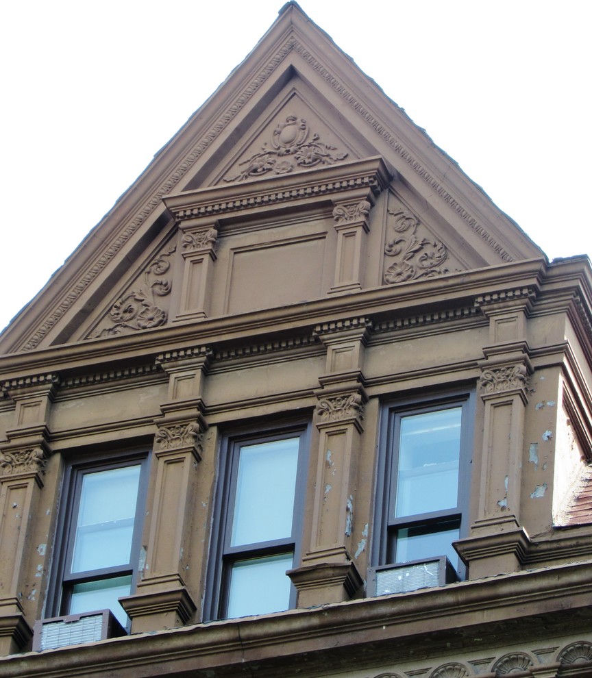 Example of a classic red three-story stucco house exterior design in New York