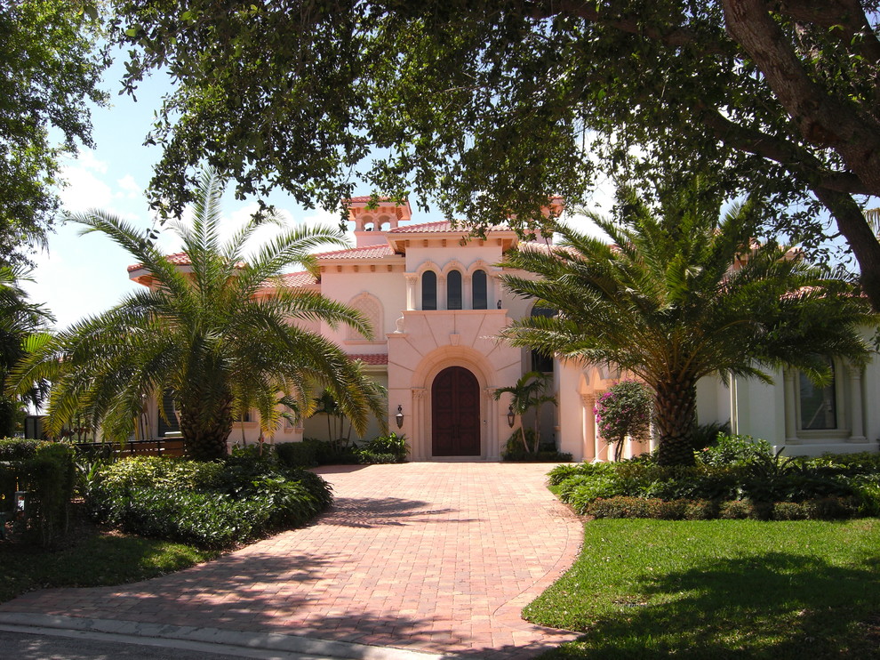 Example of a huge tuscan pink two-story stucco exterior home design in Miami with a hip roof