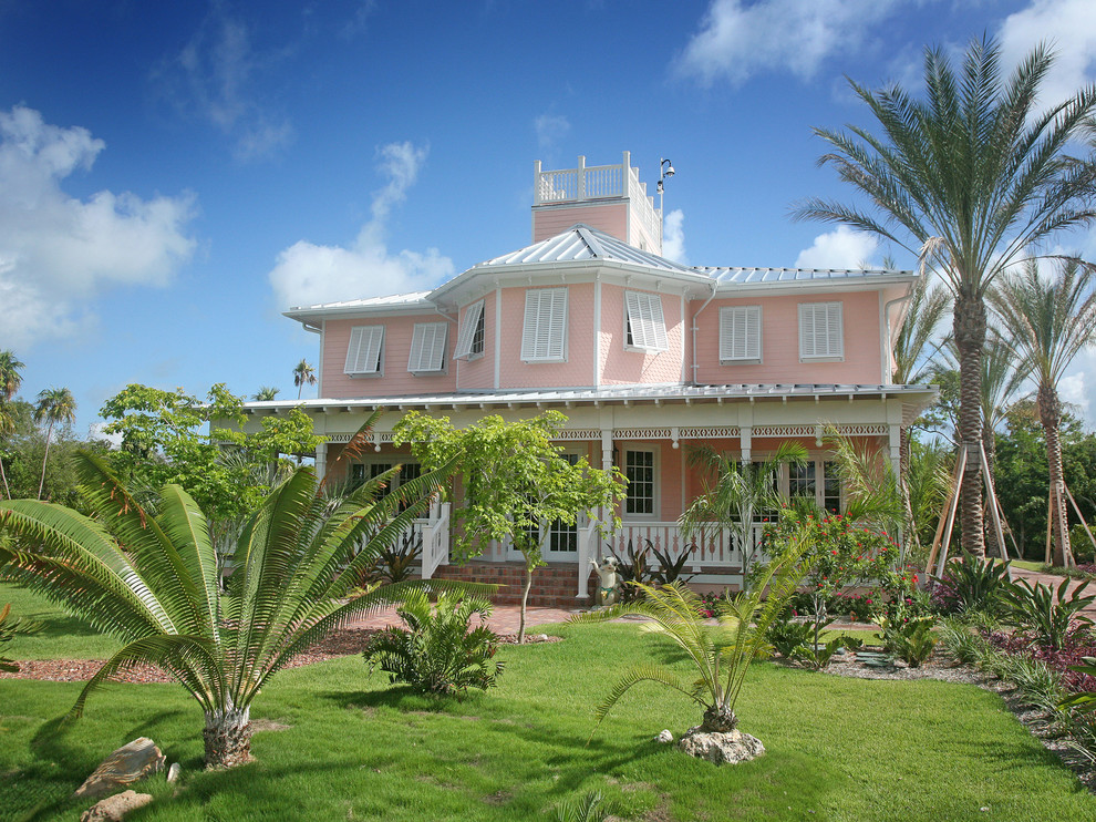 Cette photo montre une façade de maison rose exotique à un étage.