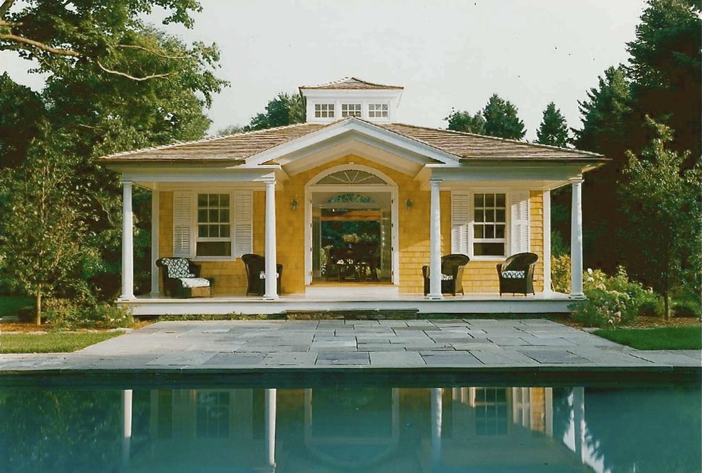 Imagen de fachada amarilla ecléctica de tamaño medio de una planta con revestimiento de madera y tejado a cuatro aguas