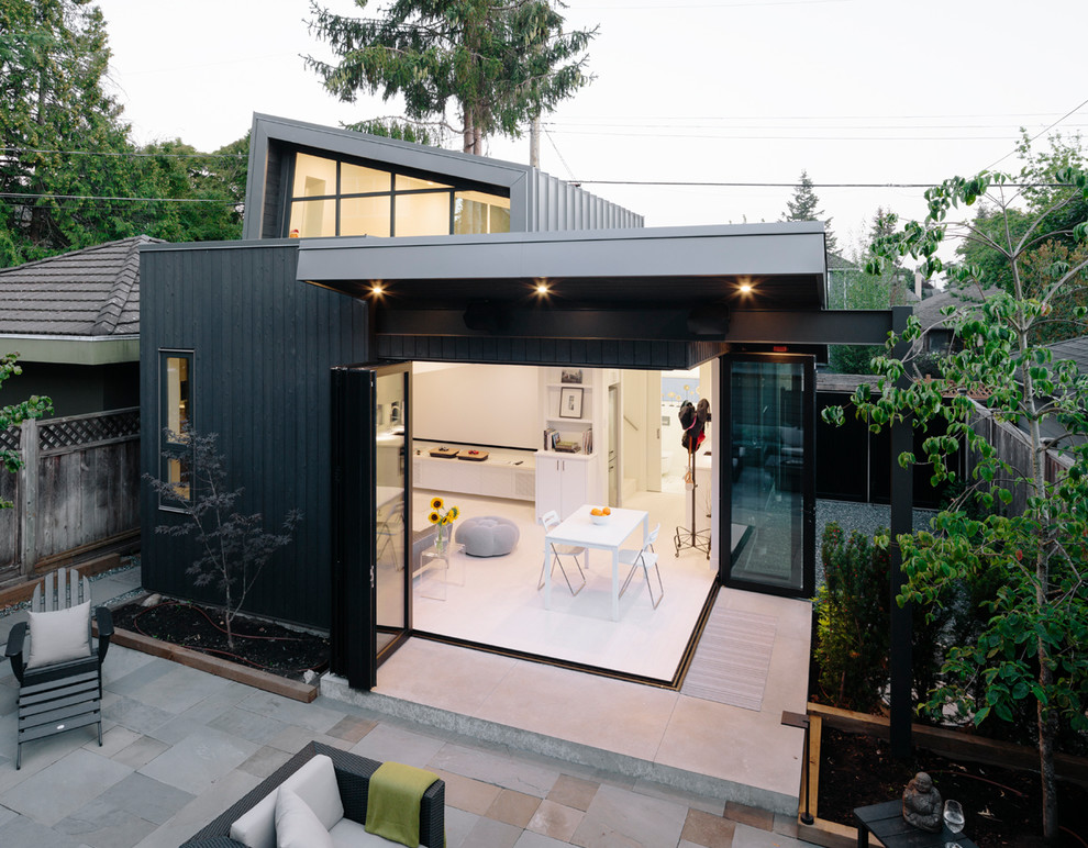 Kleine, Zweistöckige Moderne Holzfassade Haus mit schwarzer Fassadenfarbe, Flachdach und Blechdach in Vancouver
