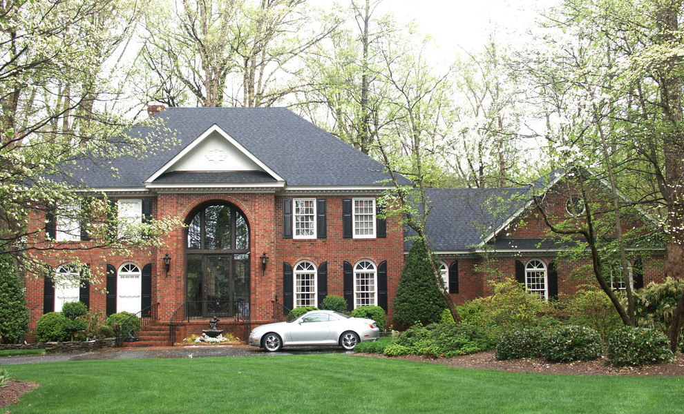 Large traditional red two-story brick exterior home idea in Raleigh