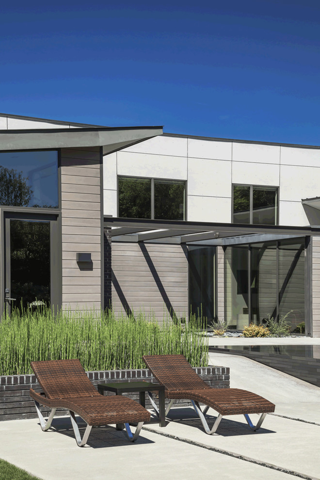Inspiration pour une très grande façade de maison grise minimaliste en brique à un étage avec un toit en appentis et un toit en métal.