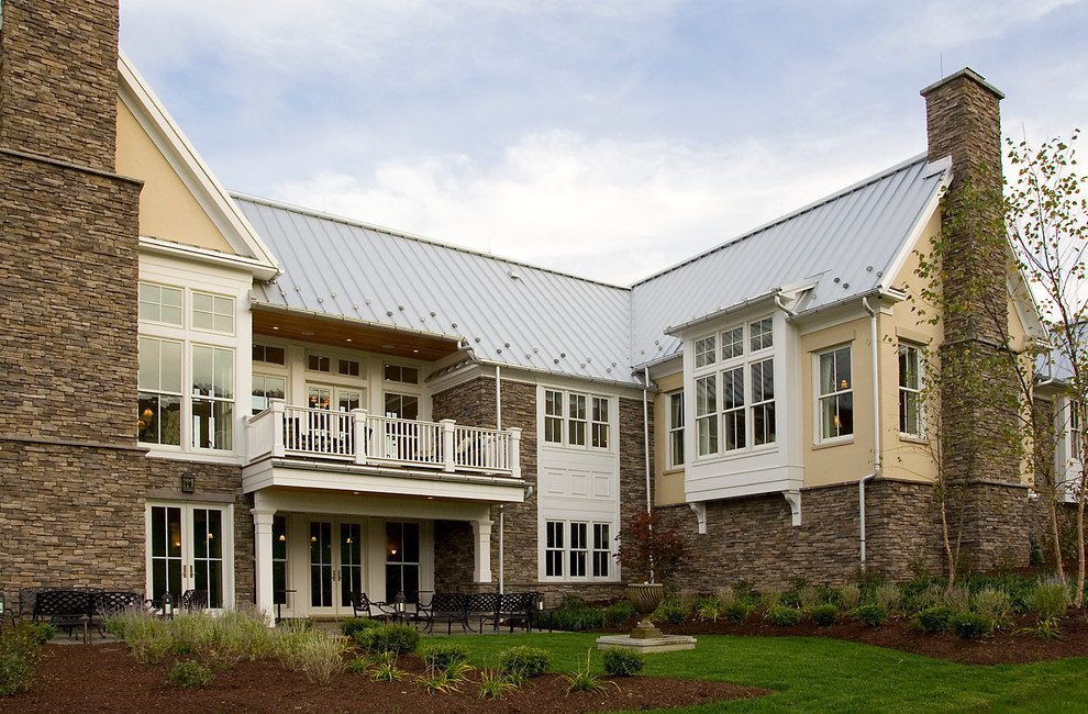 Diseño de fachada beige de estilo de casa de campo grande de dos plantas con revestimientos combinados
