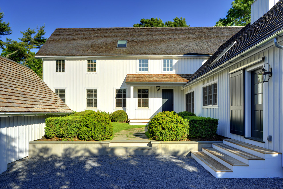 Foto della facciata di una casa grande bianca classica a due piani con rivestimento in legno e tetto a capanna