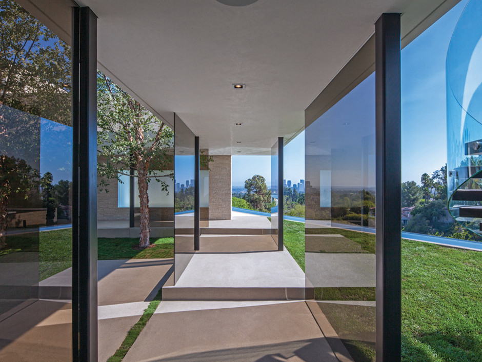 This is an example of a medium sized and beige contemporary glass house exterior in Los Angeles with three floors.