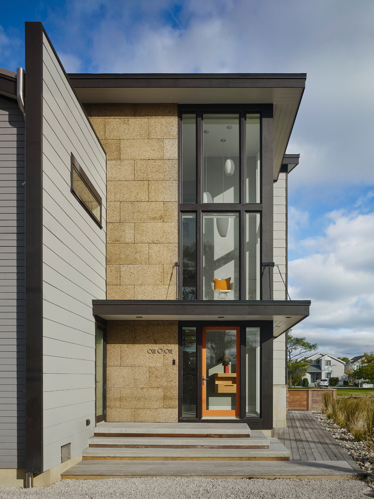 Foto della facciata di una casa piccola grigia contemporanea a due piani con rivestimento con lastre in cemento e copertura in metallo o lamiera