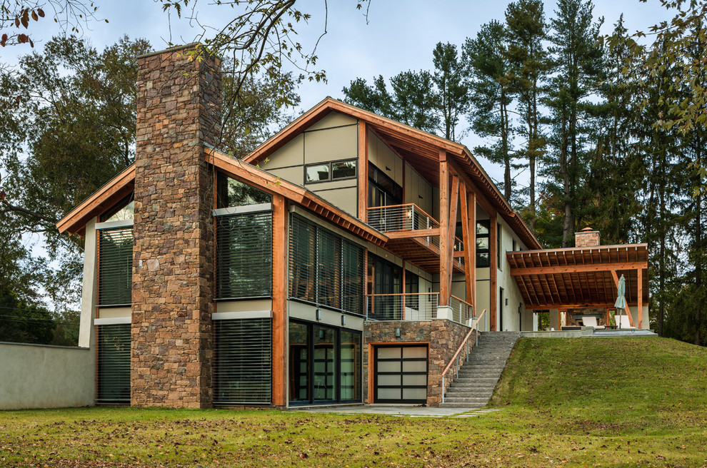 Modelo de fachada de casa beige contemporánea grande de dos plantas con tejado a dos aguas, revestimiento de estuco y tejado de metal
