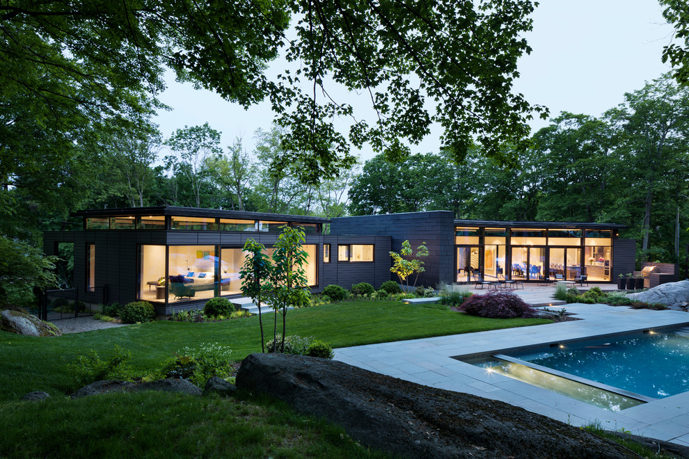 Réalisation d'une façade de maison noire design de plain-pied avec un toit plat et un revêtement mixte.