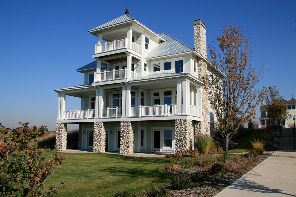 Esempio della facciata di una casa grande grigia a tre piani con rivestimento con lastre in cemento e tetto a padiglione