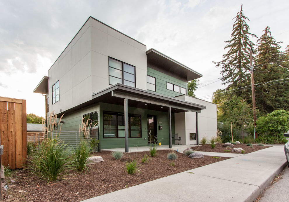 This is an example of a medium sized and green modern house exterior in Other with three floors, concrete fibreboard cladding and a flat roof.