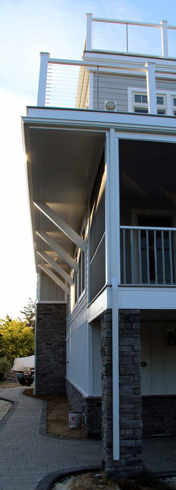 Esempio della facciata di una casa grande grigia stile marinaro a tre piani con rivestimento con lastre in cemento