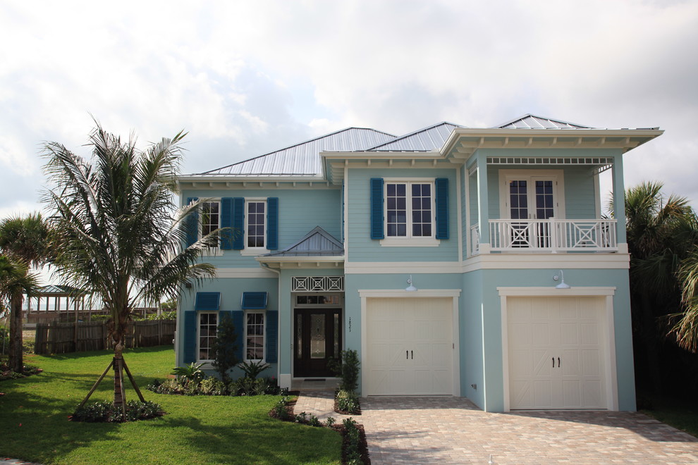 Diseño de fachada de casa azul costera grande de dos plantas con revestimiento de estuco y tejado a cuatro aguas