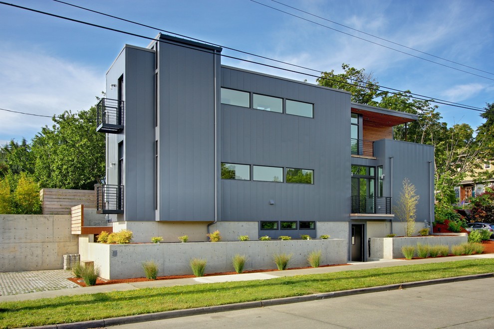 Exemple d'une petite façade de maison grise et métallique tendance à deux étages et plus avec un toit plat.