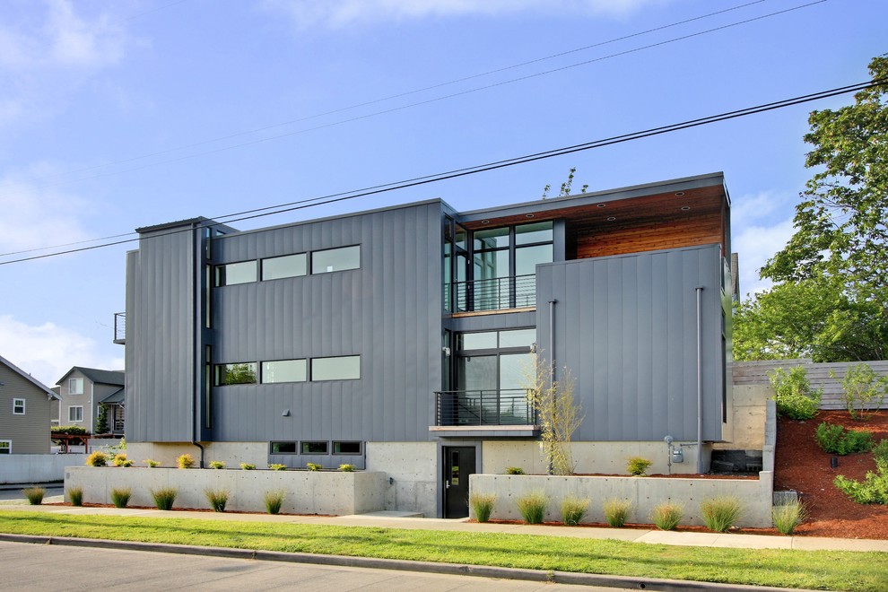 Inspiration för små moderna grå hus, med tre eller fler plan, metallfasad och platt tak