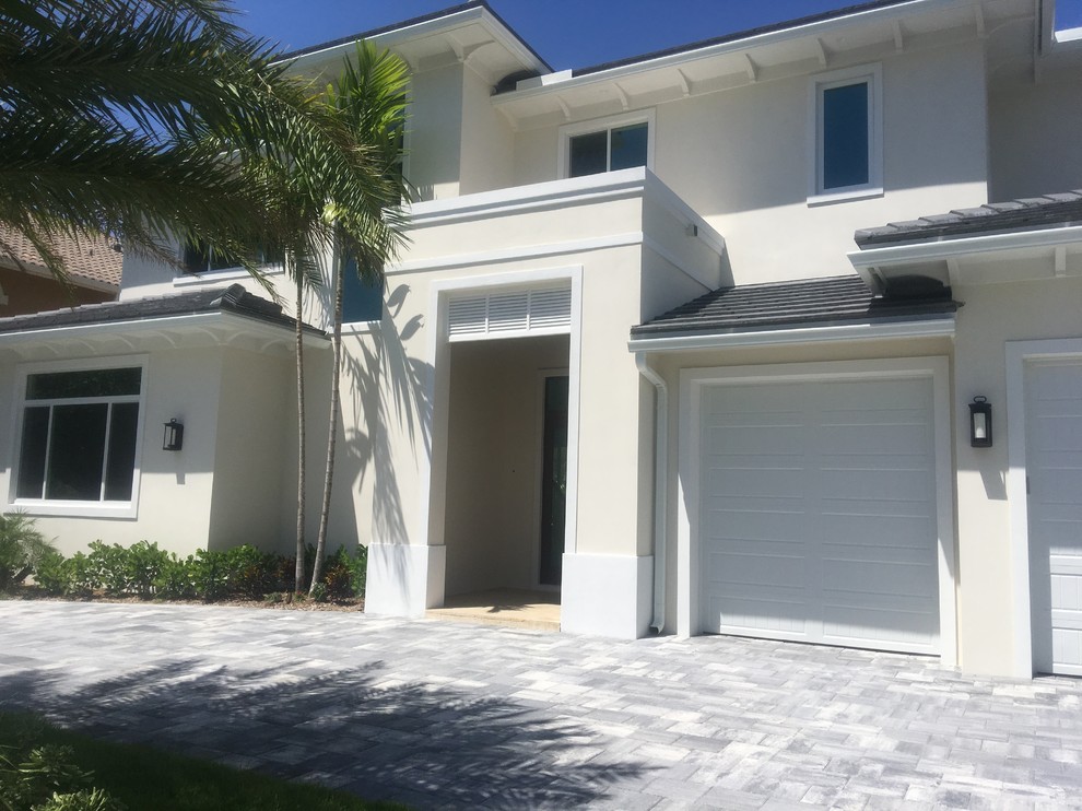 Example of a mid-sized beach style white two-story stucco house exterior design in Miami with a hip roof and a tile roof