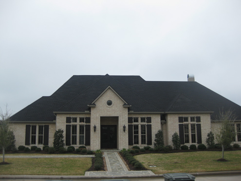 Mid-sized transitional beige two-story stone gable roof photo in Houston