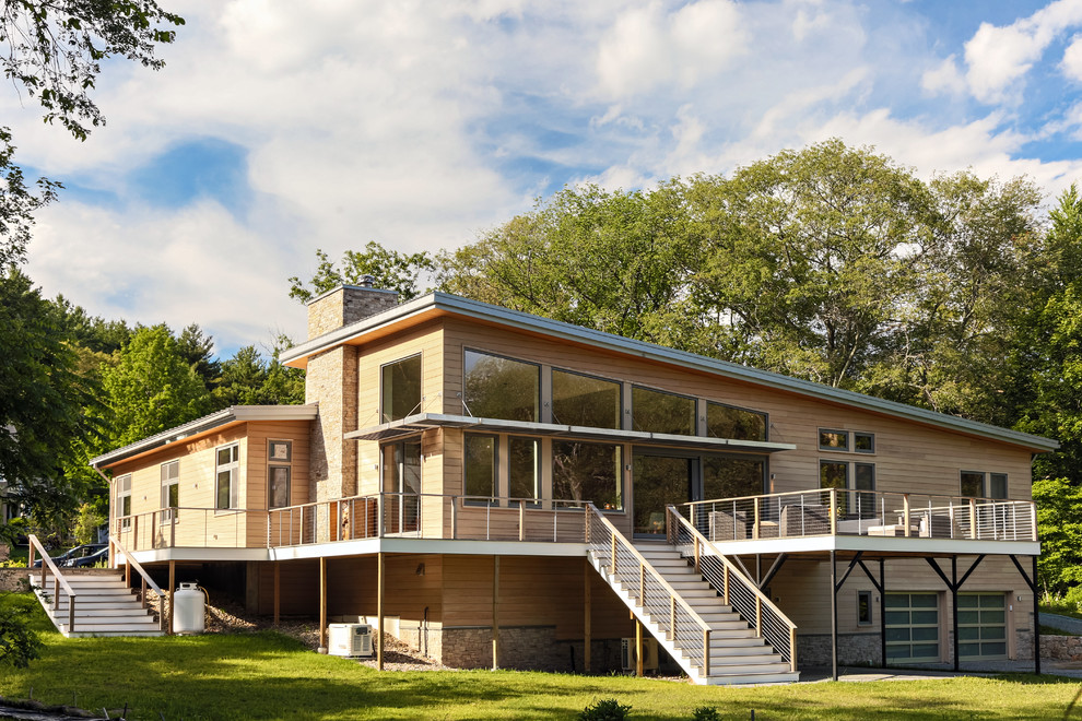 Diseño de fachada de casa beige moderna de tamaño medio de dos plantas con revestimiento de madera, tejado de un solo tendido y tejado de metal