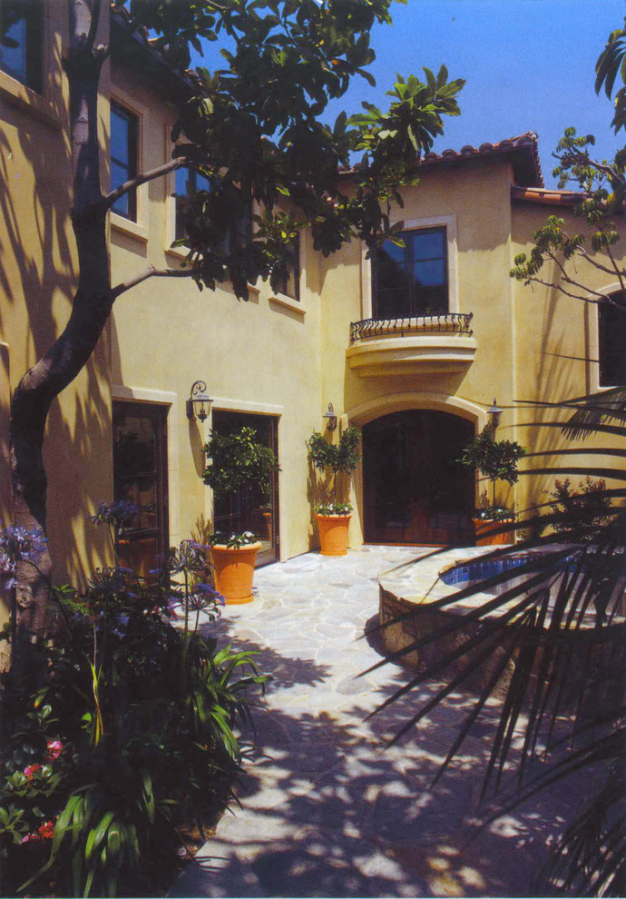 Diseño de fachada beige mediterránea grande de dos plantas con revestimiento de estuco y tejado plano