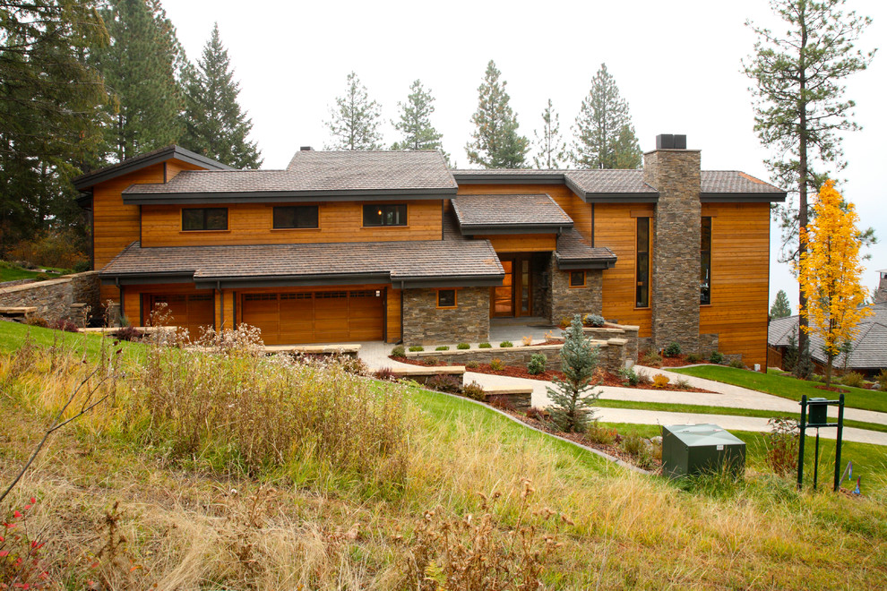 Cette image montre une très grande façade de maison marron craftsman en bois à un étage avec un toit à croupette.
