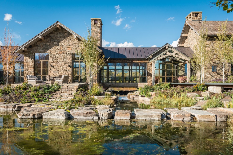 Example of a mountain style stone exterior home design in Other with a metal roof