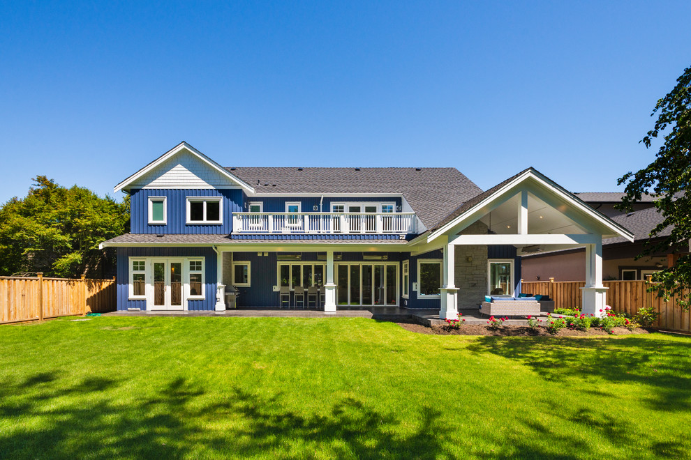 Cette image montre une grande façade de maison bleue traditionnelle en bois à un étage avec un toit en shingle.