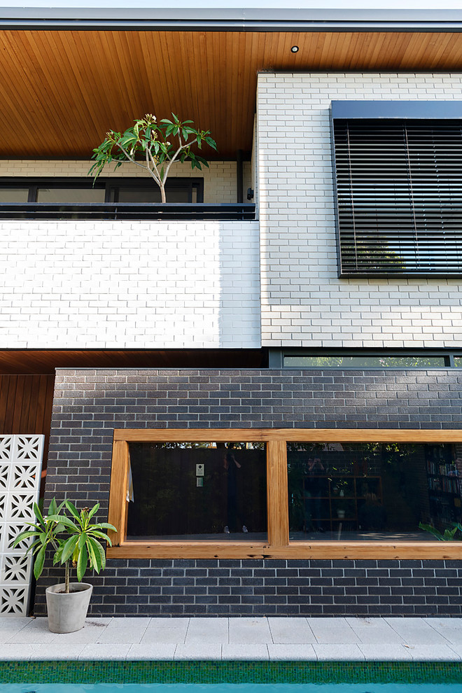 Imagen de fachada de casa retro grande de dos plantas con revestimiento de ladrillo y tejado plano