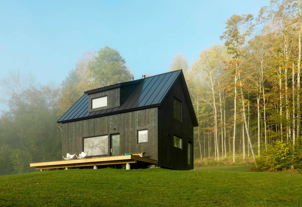 Idée de décoration pour une petite façade de maison noire nordique en bois à un étage avec un toit à deux pans et un toit en métal.