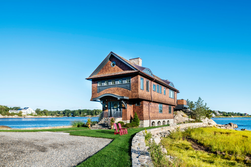 На фото: двухэтажный, деревянный, коричневый частный загородный дом в морском стиле с двускатной крышей с