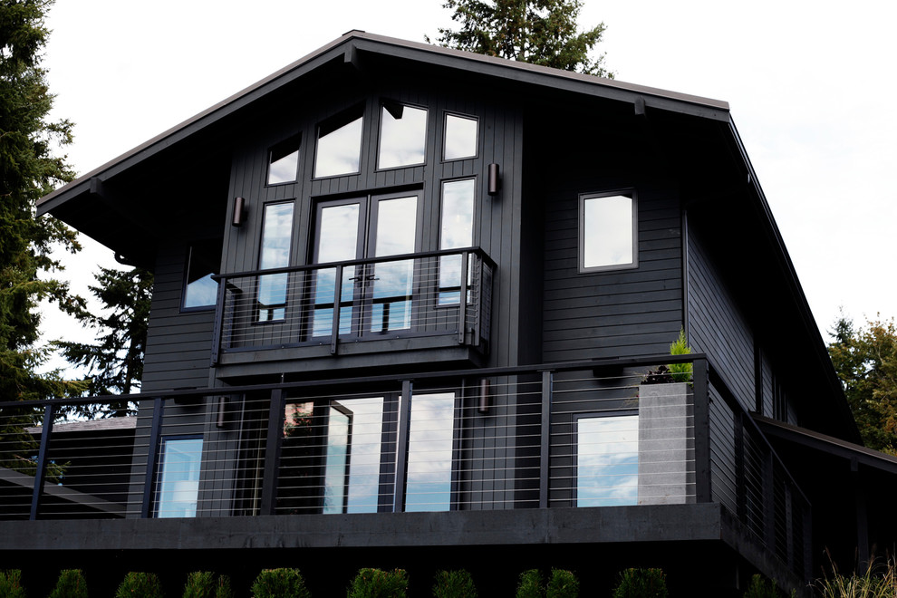 Immagine della facciata di una casa grande grigia contemporanea a due piani con rivestimento in legno e tetto a mansarda
